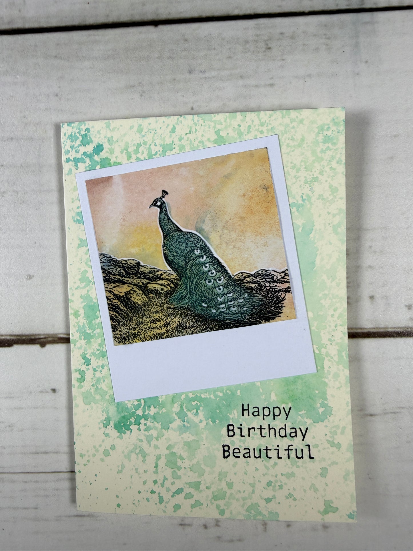 Greeting card with a peacock illustration and 'Happy Birthday Beautiful' text on a textured green background.