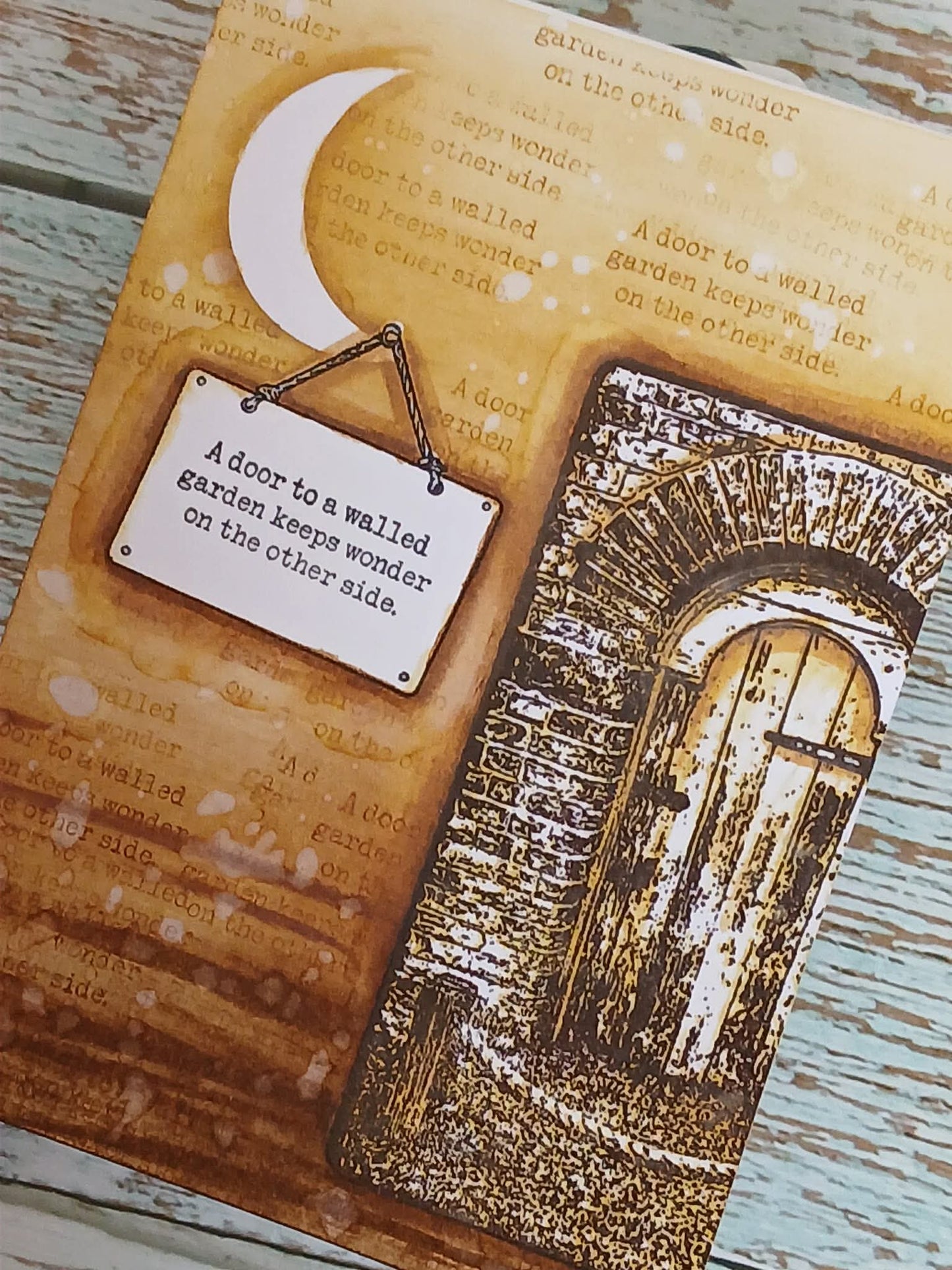 Decorative book with a moon design, text, and an arch illustration on a wooden surface.