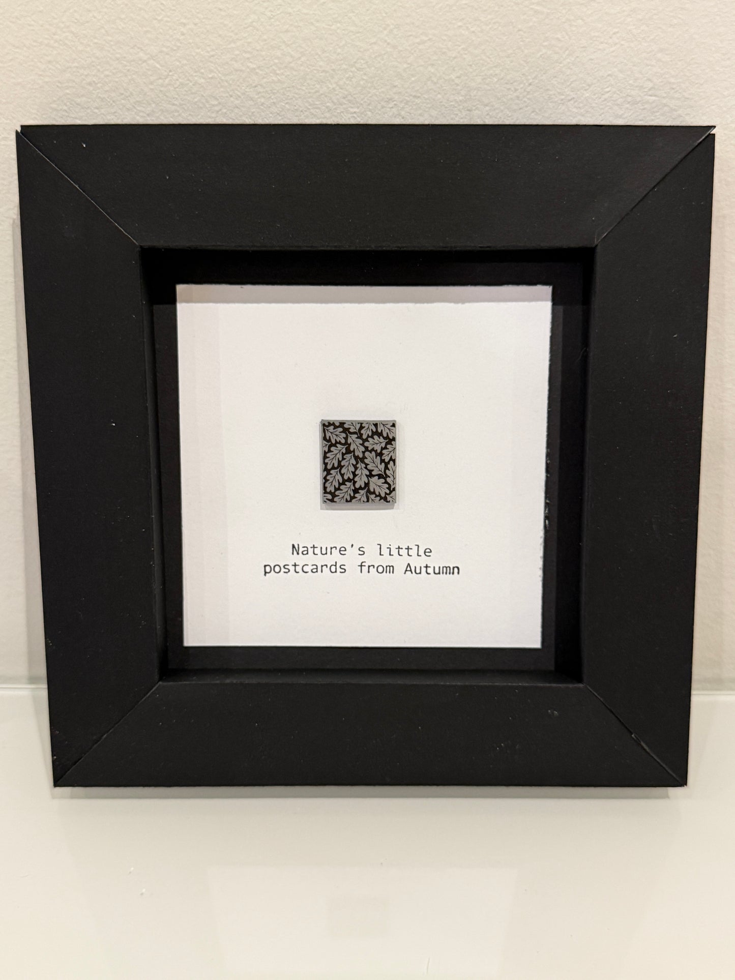 Framed artwork with a QR code and text on a white wall