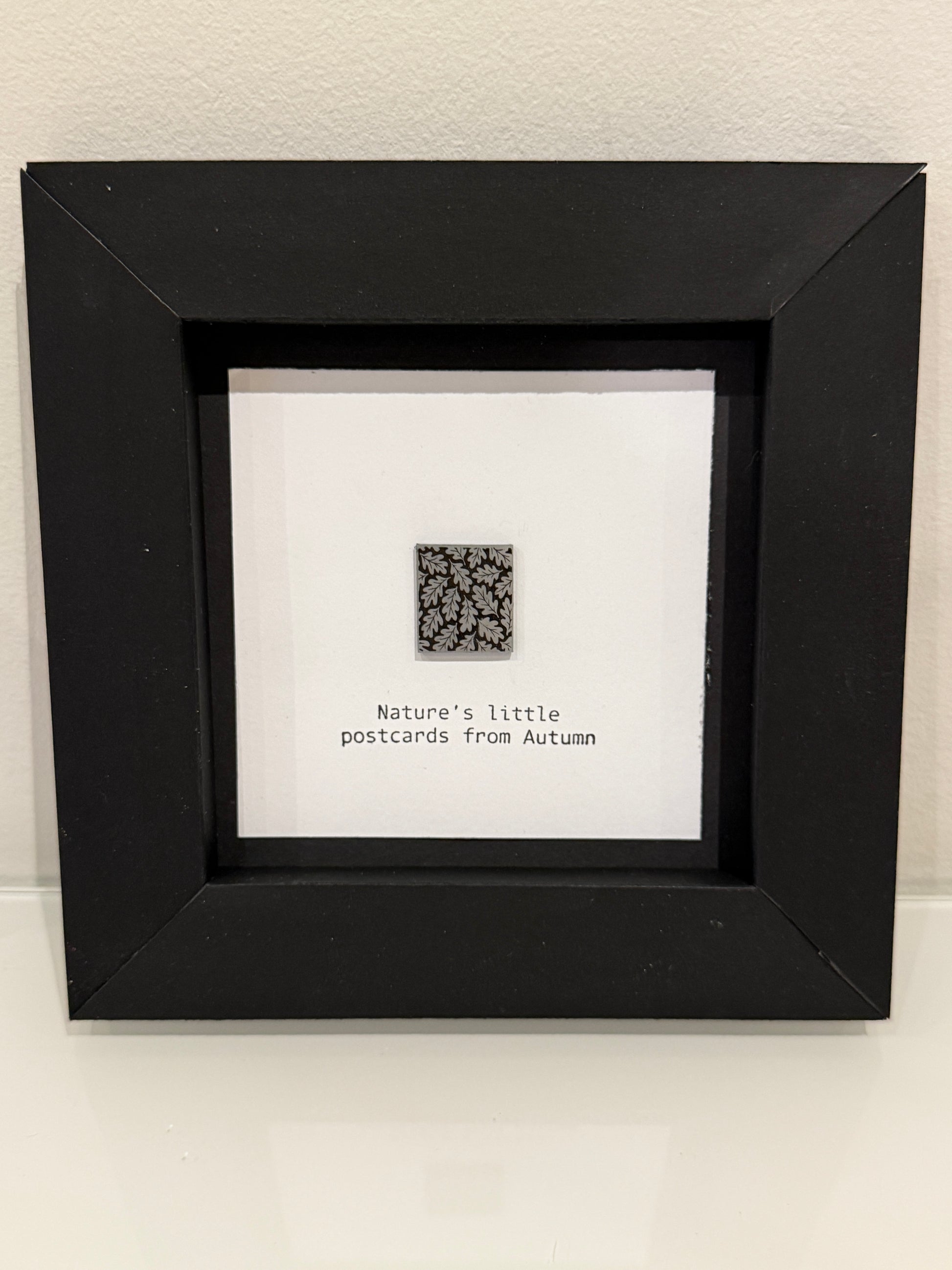 Framed artwork with a QR code and text on a white wall