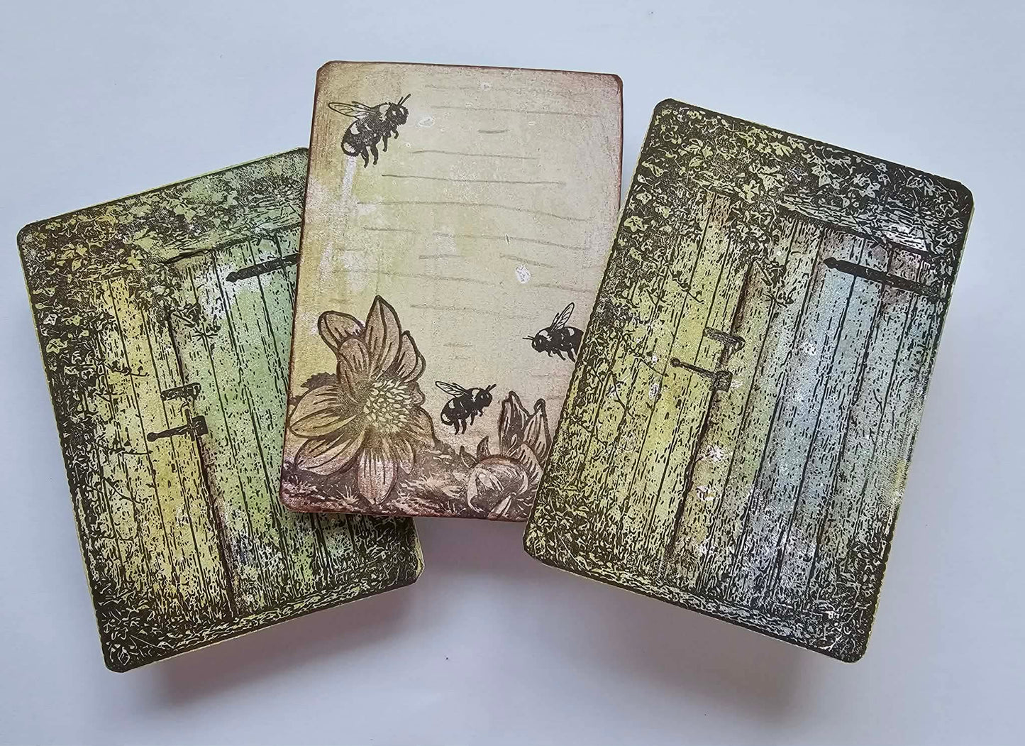 Three decorative cards with floral and bee designs on a white background