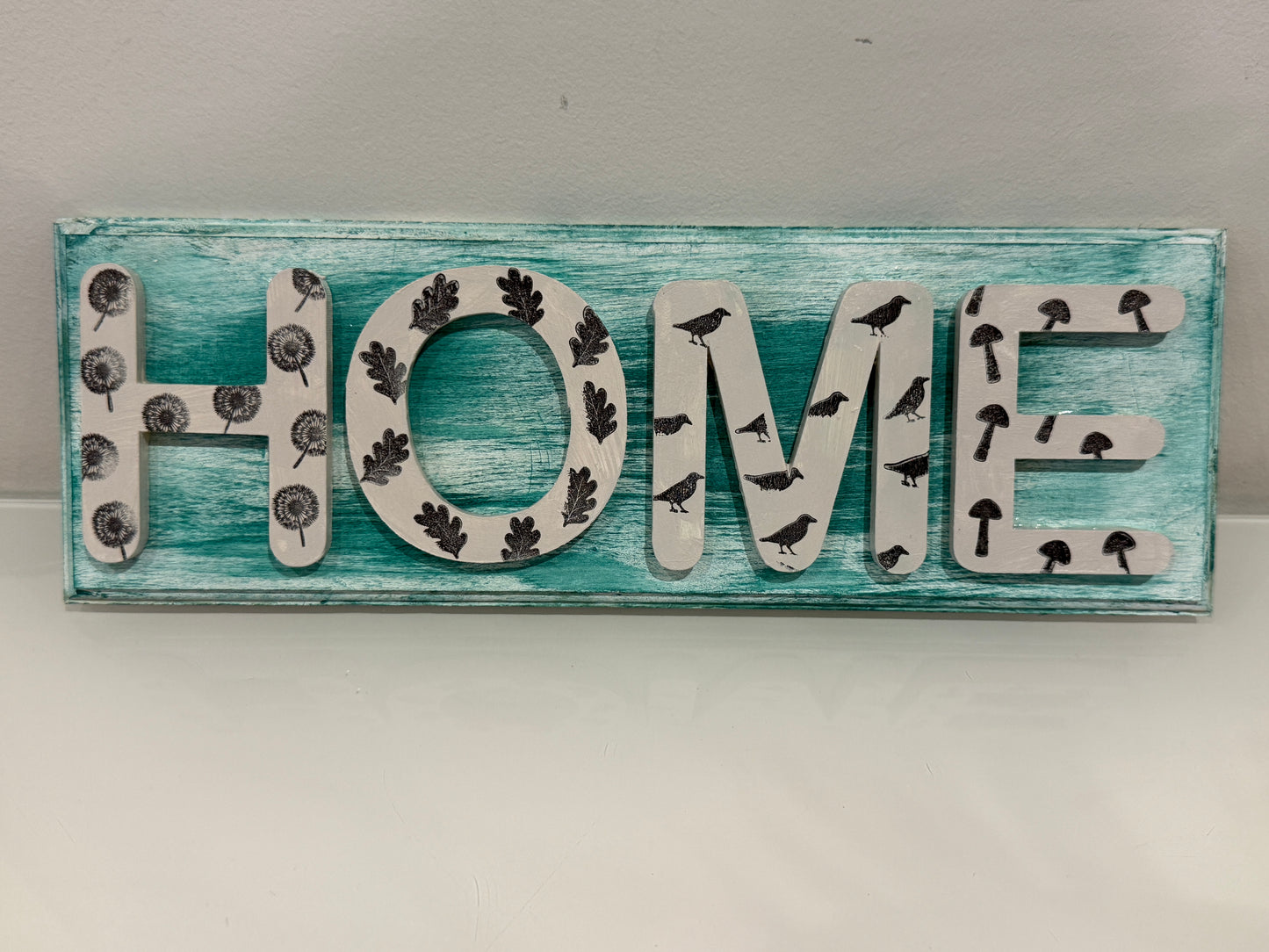 Decorative sign with 'HOME' letters on a wooden background