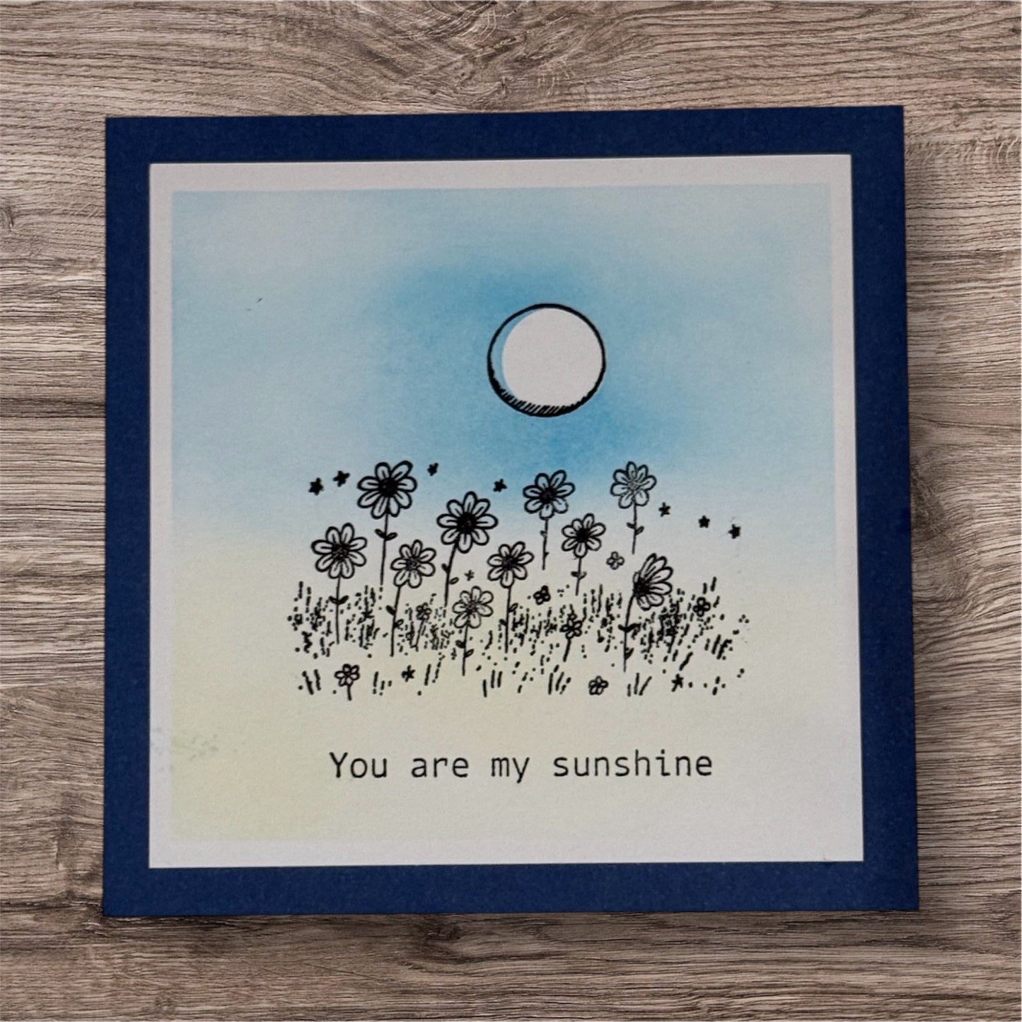Card with floral design and 'You are my sunshine' text on a wooden surface