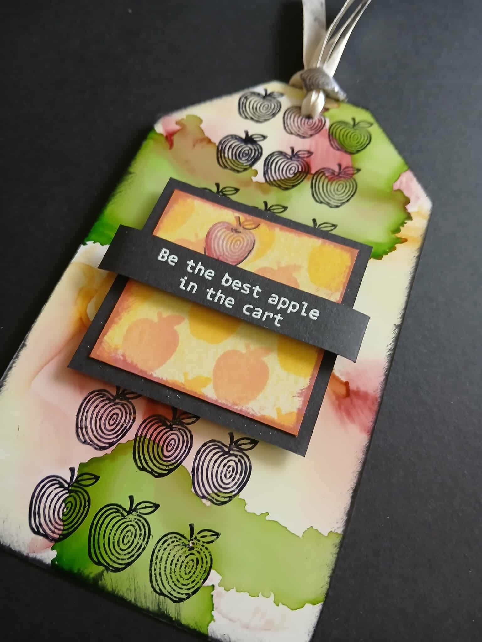 Decorative tag with apple design and text 'Be the best apple in the cart' on a black background