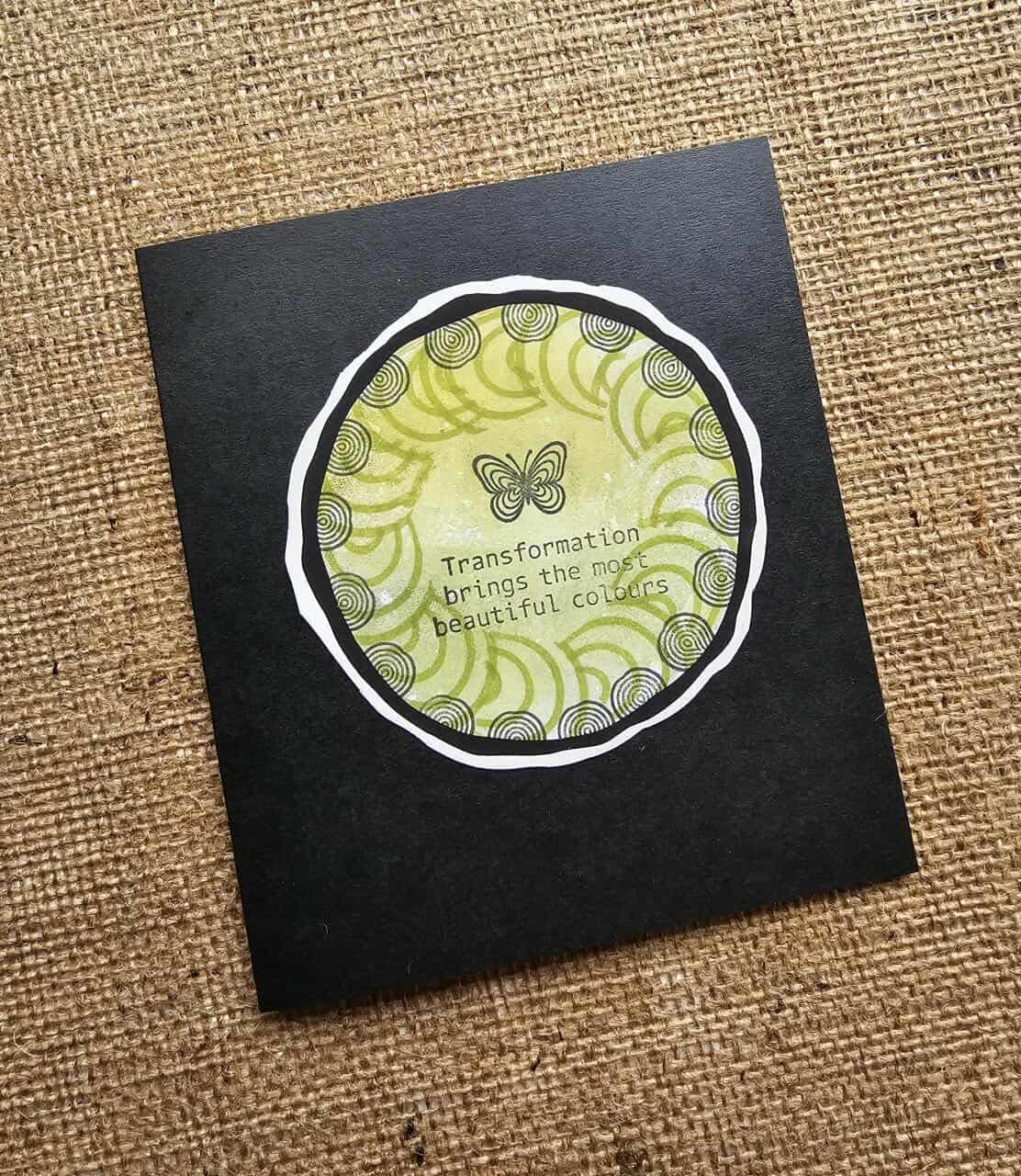 Black card with a circular design featuring a butterfly and text on a textured brown background