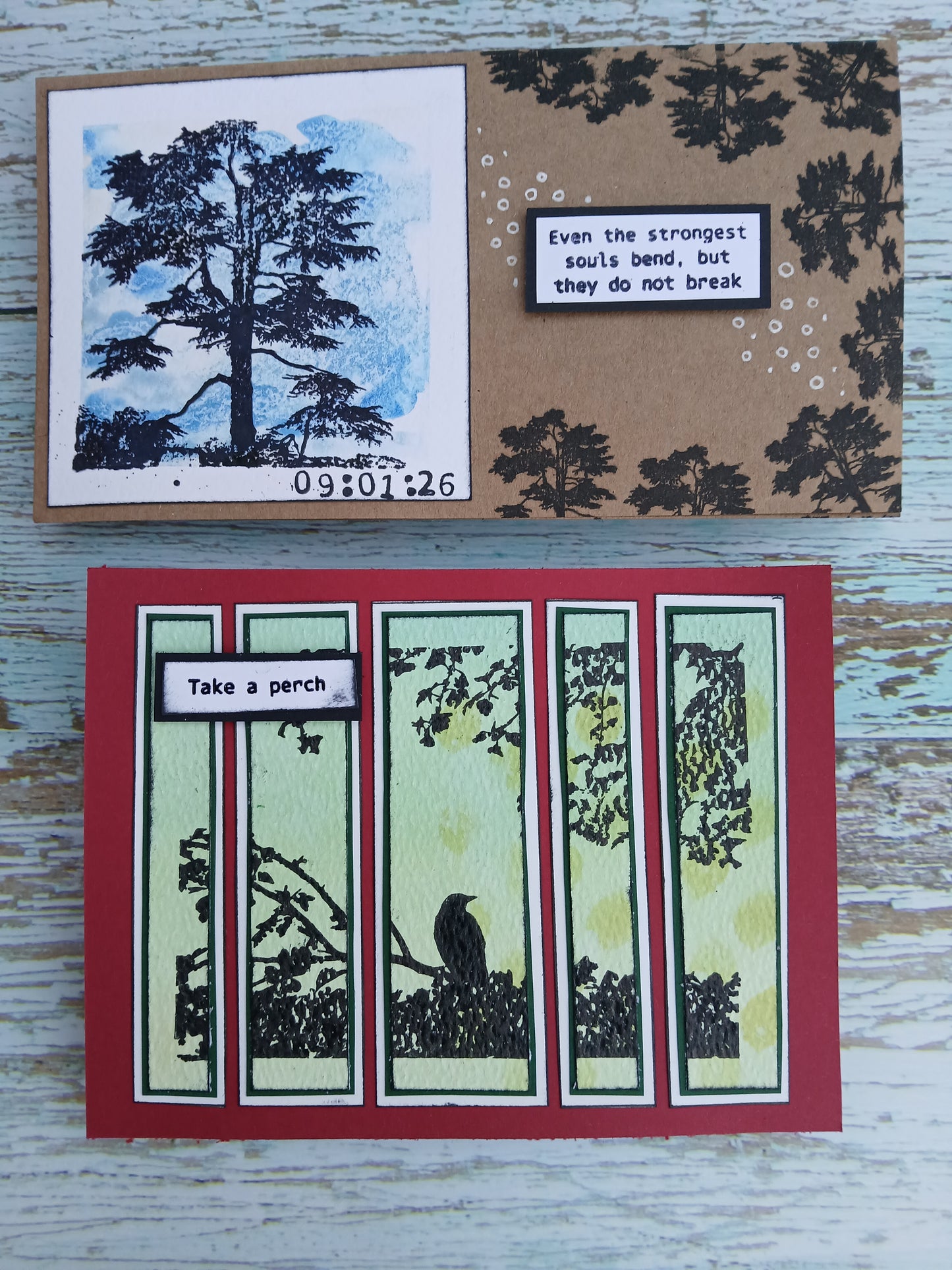 Two handmade cards with tree designs and text on a wooden surface