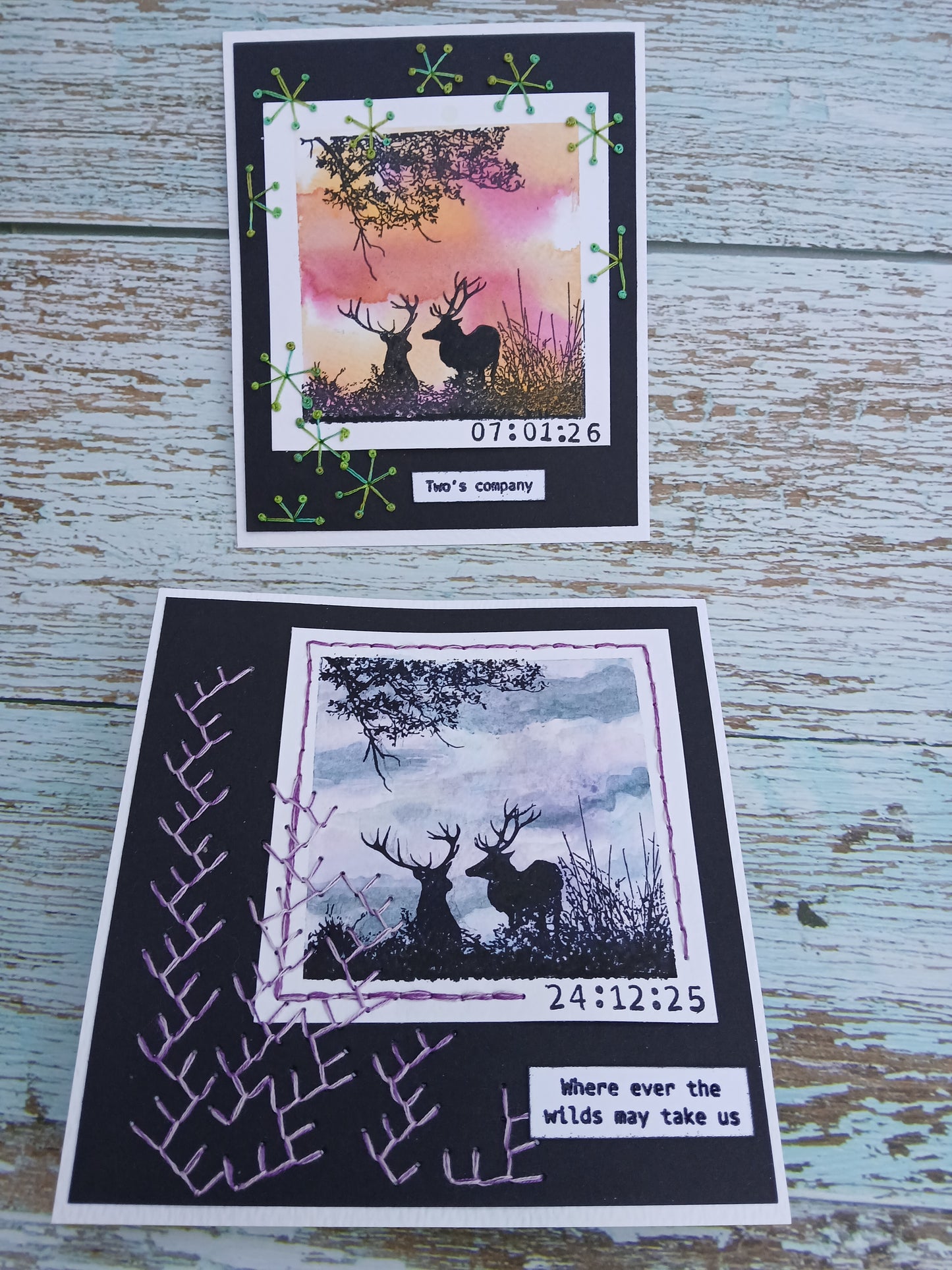 Two artistic cards with nature-themed designs on a wooden surface