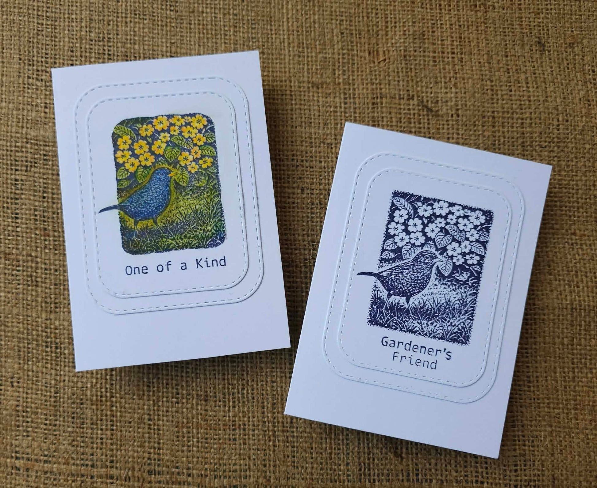 Two greeting cards with bird illustrations on a textured brown background