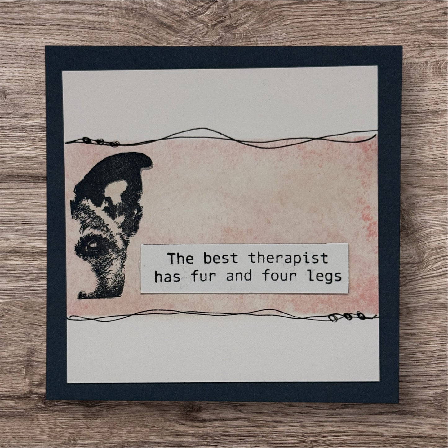 Card with dog illustration and text 'The best therapist has fur and four legs' on a wooden surface