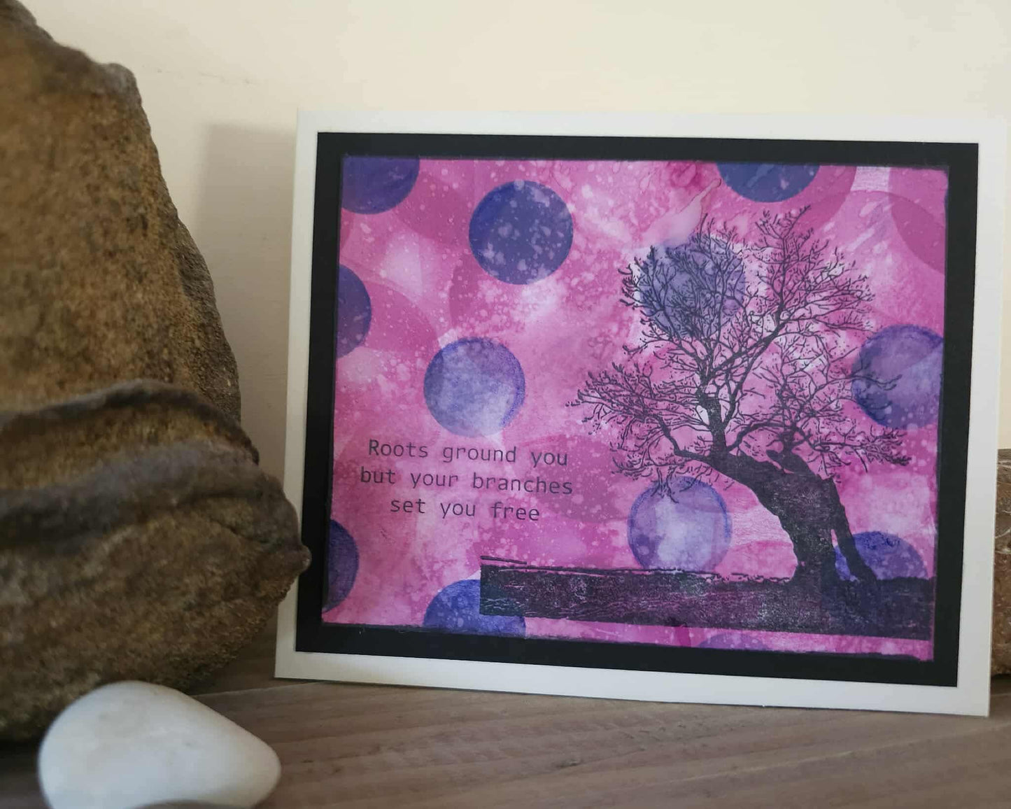 Framed artwork with a tree silhouette and motivational quote on a pink and purple polka dot background.