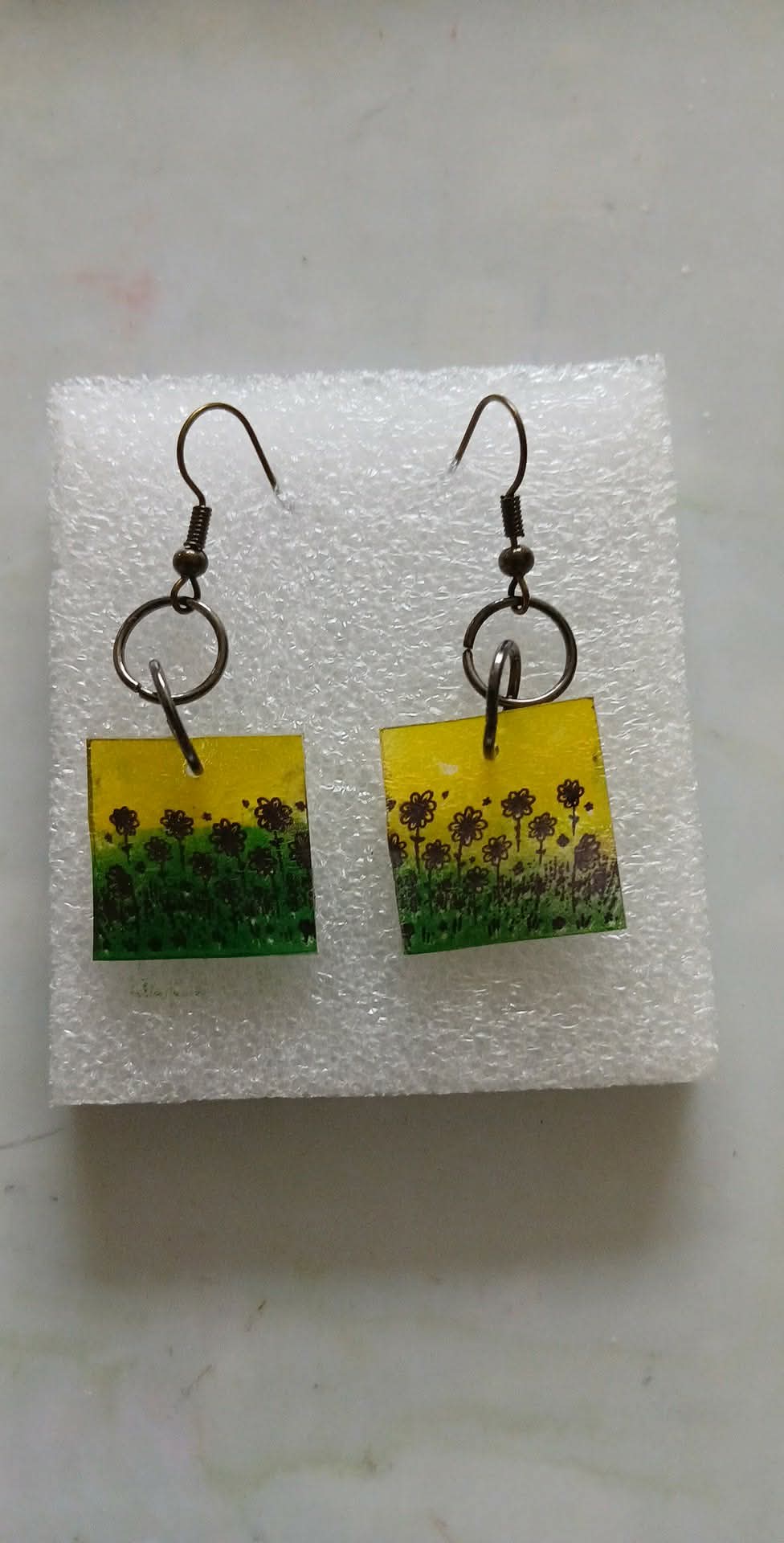 Pair of earrings with sunflower design on a white background