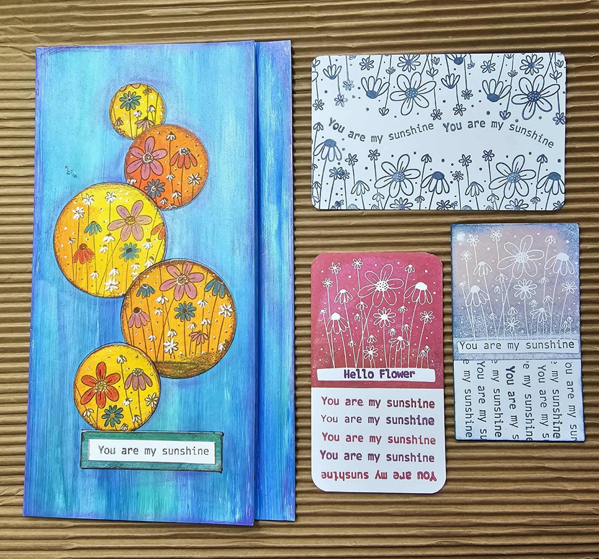 Set of greeting cards with floral designs and text on a wooden surface