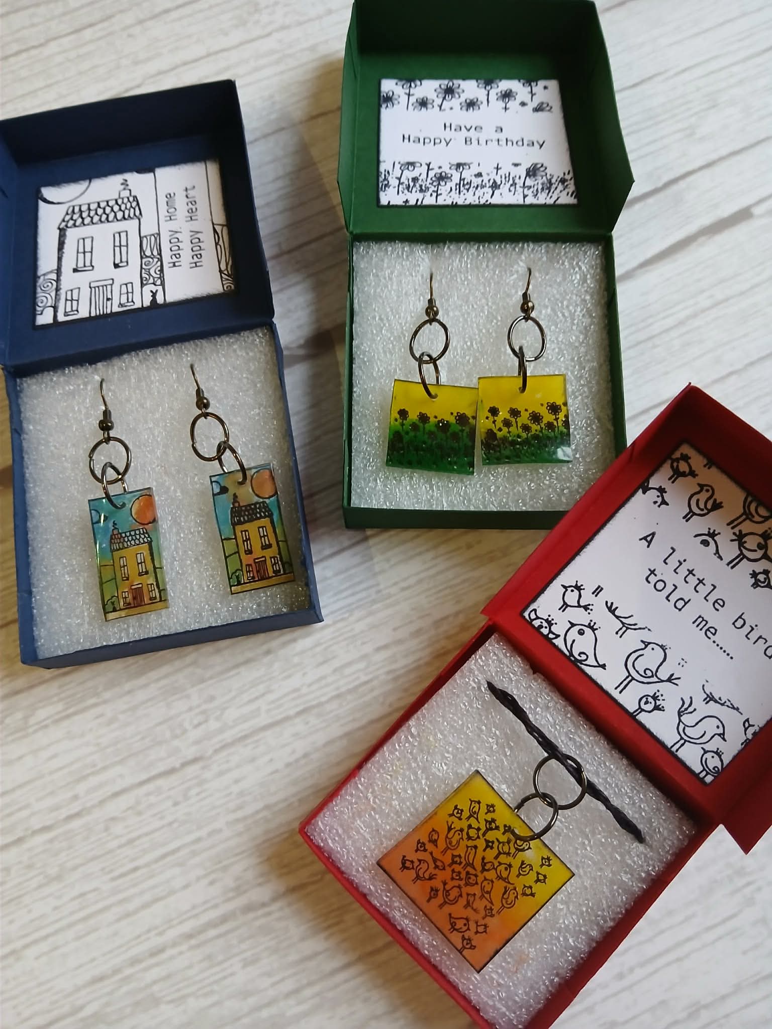 Set of earrings in open boxes on a wooden surface