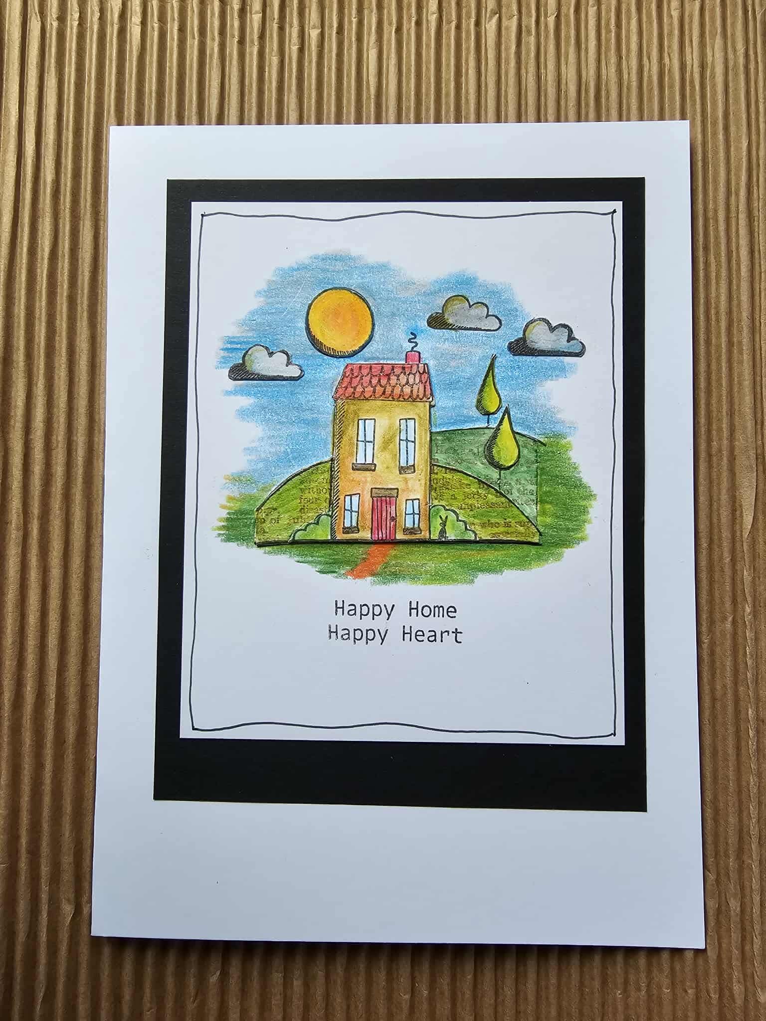 Card with a house illustration and 'Happy Home Happy Heart' text on a wooden surface