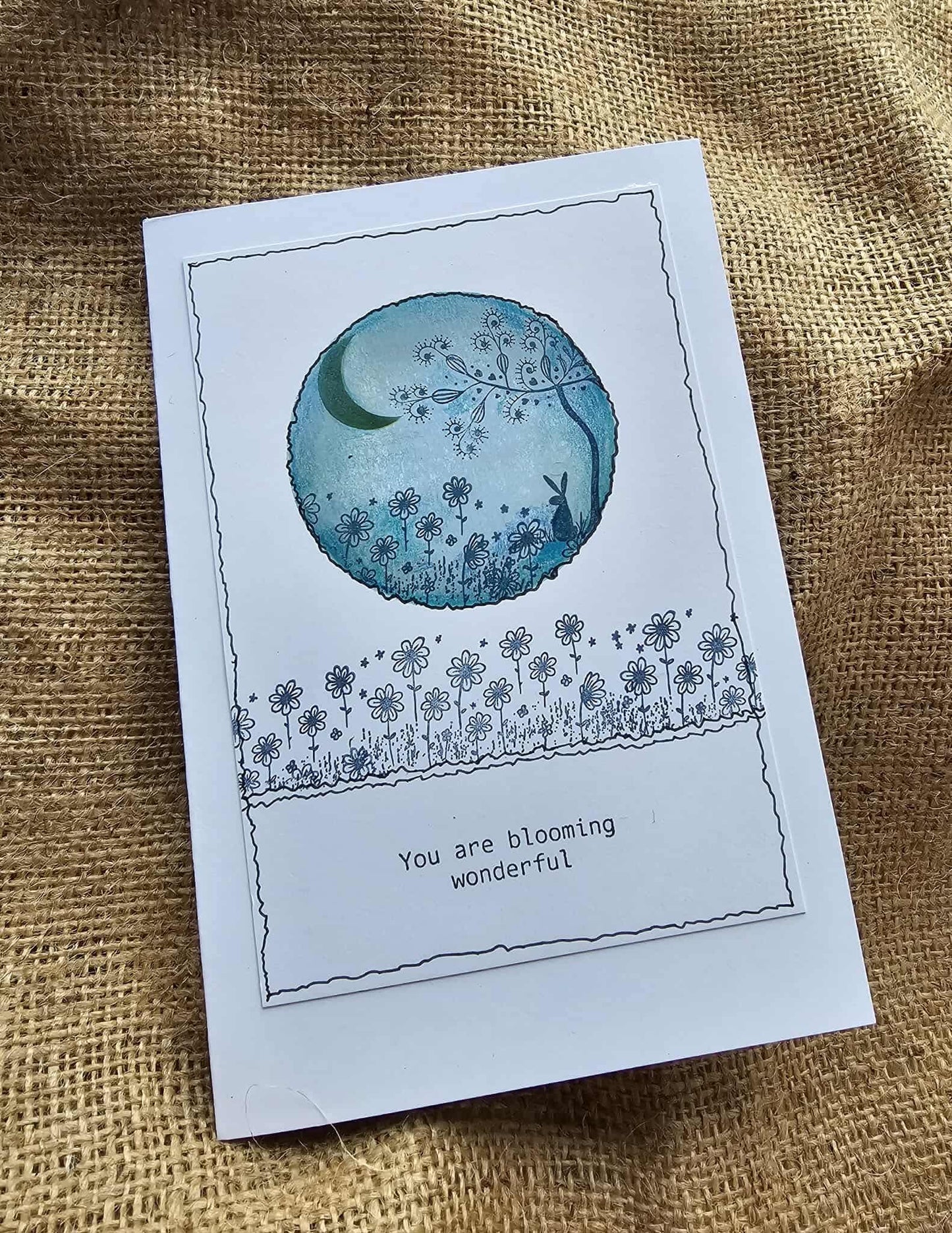 Greeting card with floral design and text 'You are blooming wonderful' on a textured fabric background