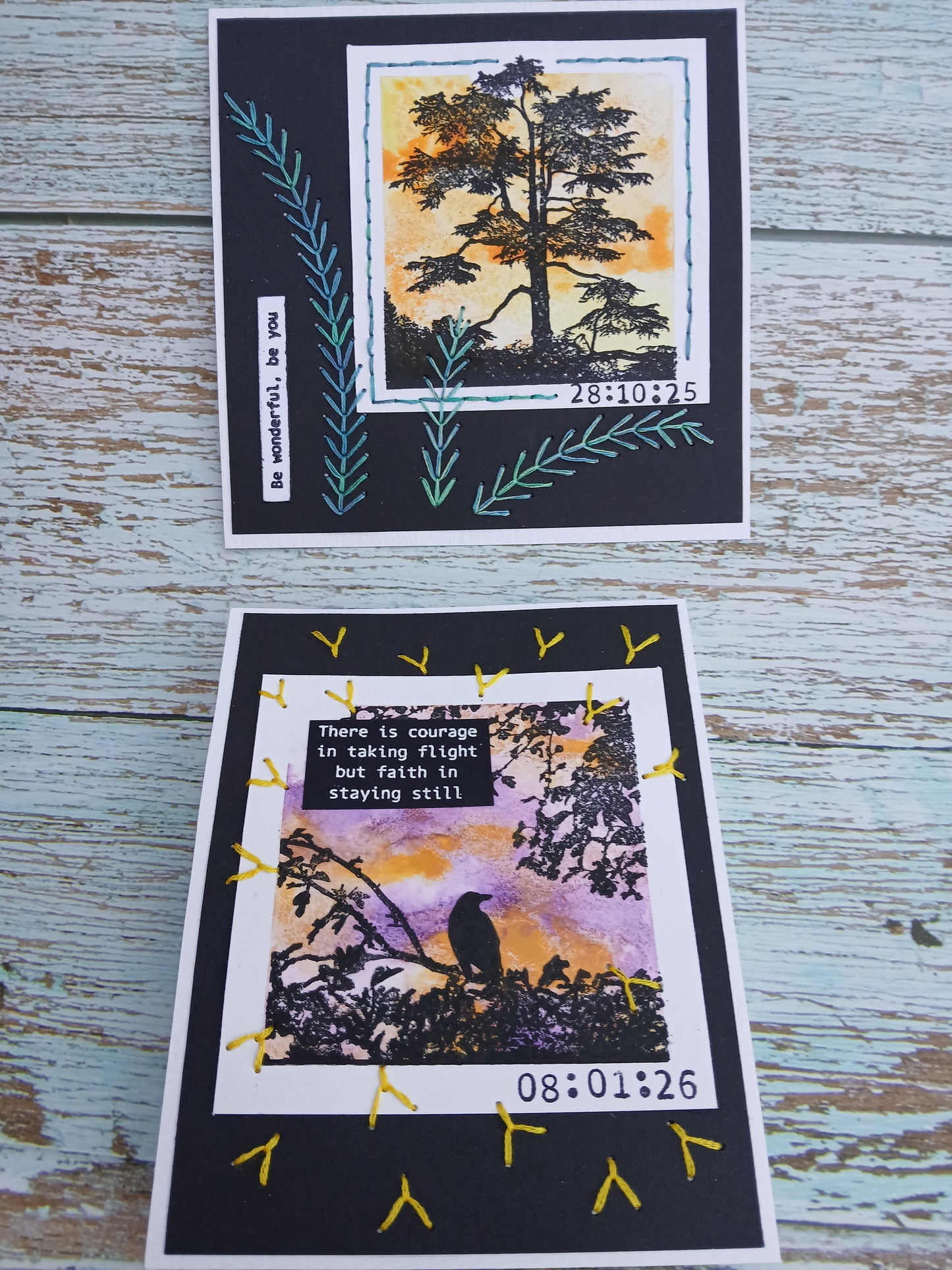 Two greeting cards with nature-themed designs on a wooden surface