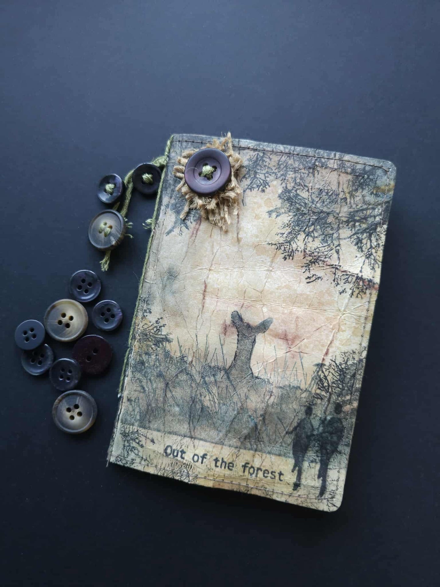 Notebook with nature-themed design and buttons on a dark background