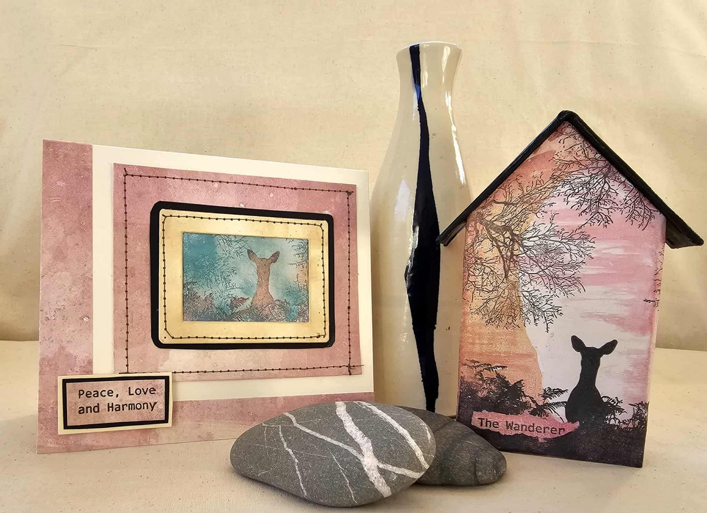 Decorative items including a framed picture, vase, and house-shaped object with a deer design on a beige background.