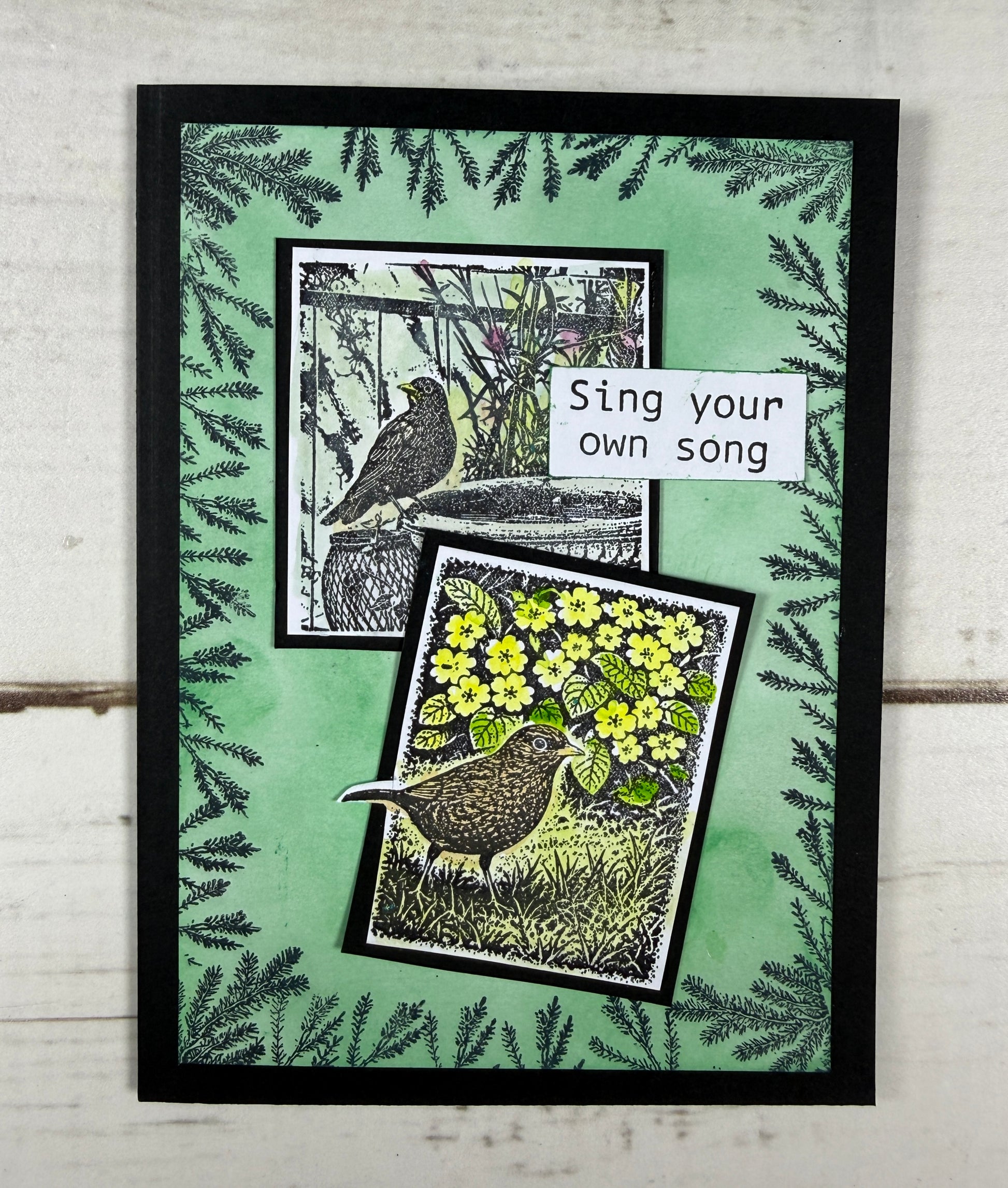 Framed artwork with bird illustrations and floral design on a green background.