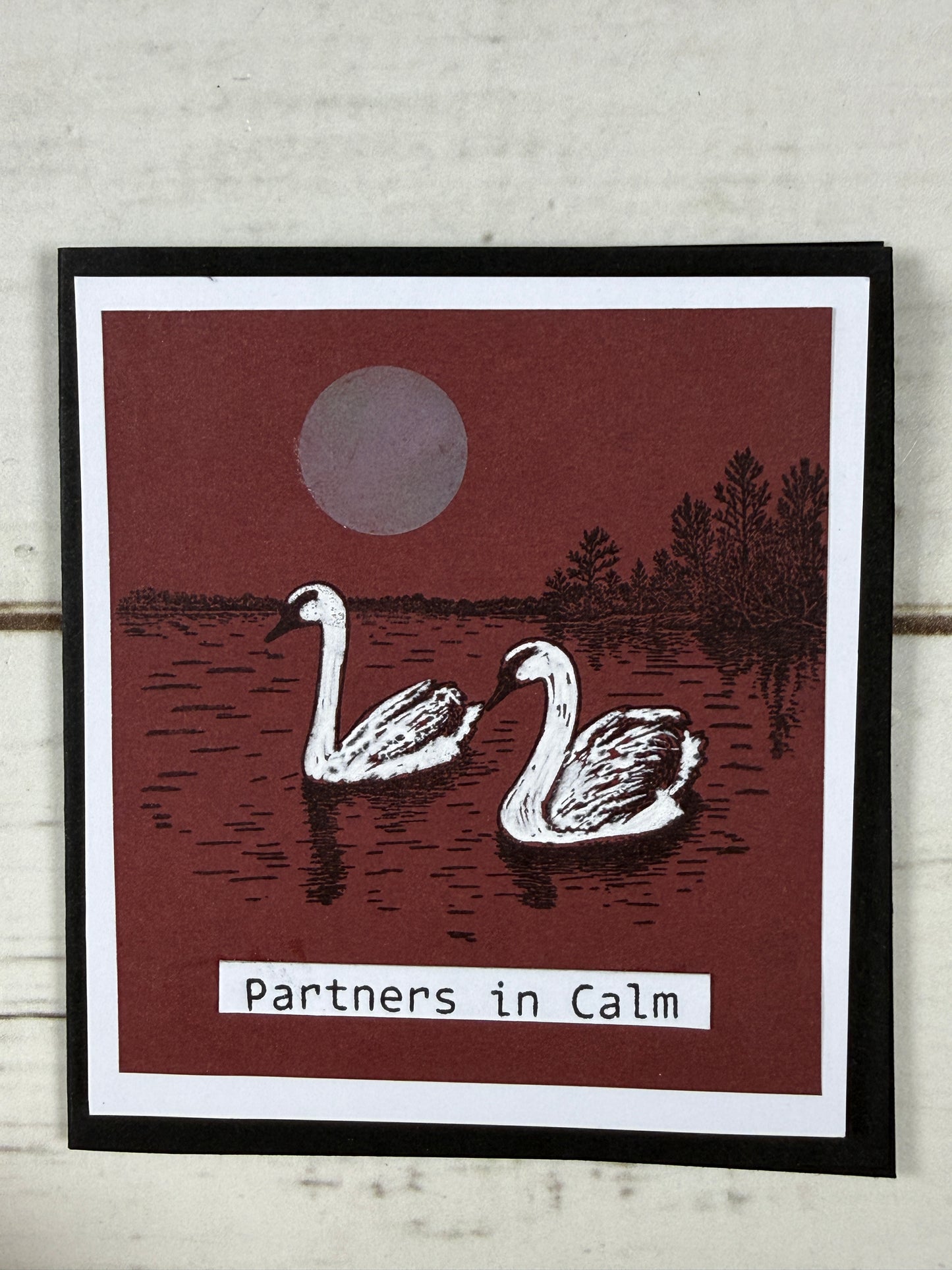 Card with flamingo design and 'partners in calm' text on a wooden surface