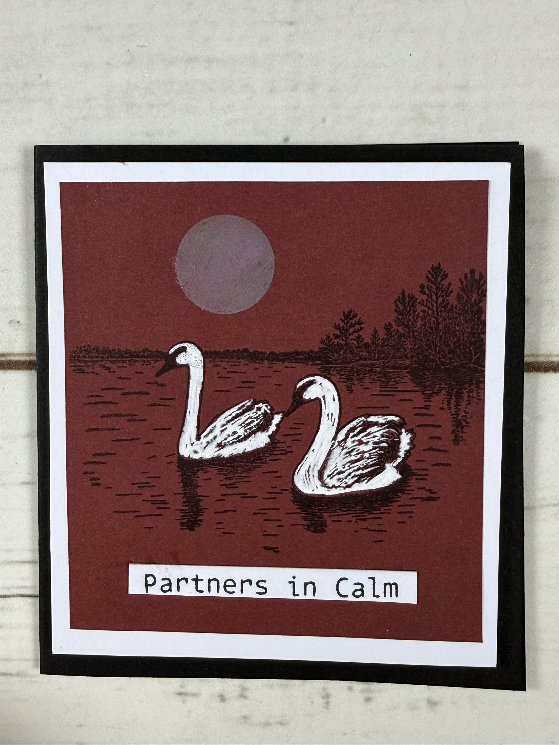 Card with flamingo design and 'partners in calm' text on a wooden surface