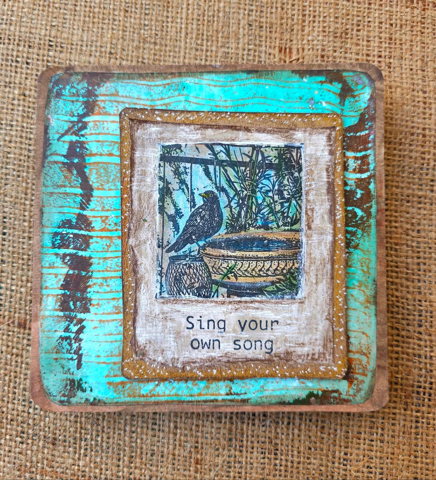 Decorative plaque with a bird illustration and text 'Sing your own song' on a textured background