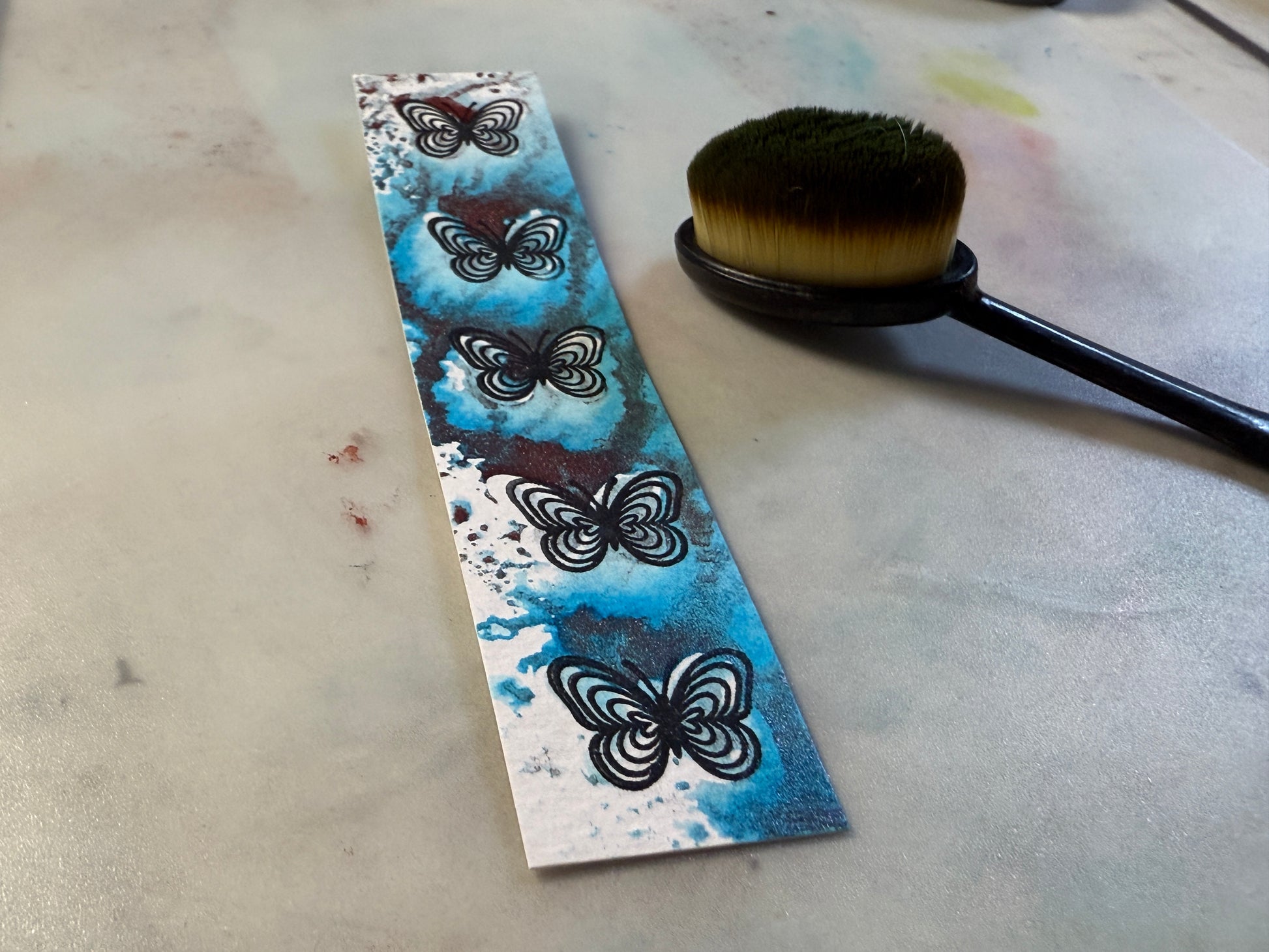 Decorative strip with butterfly pattern next to a brush on a textured surface