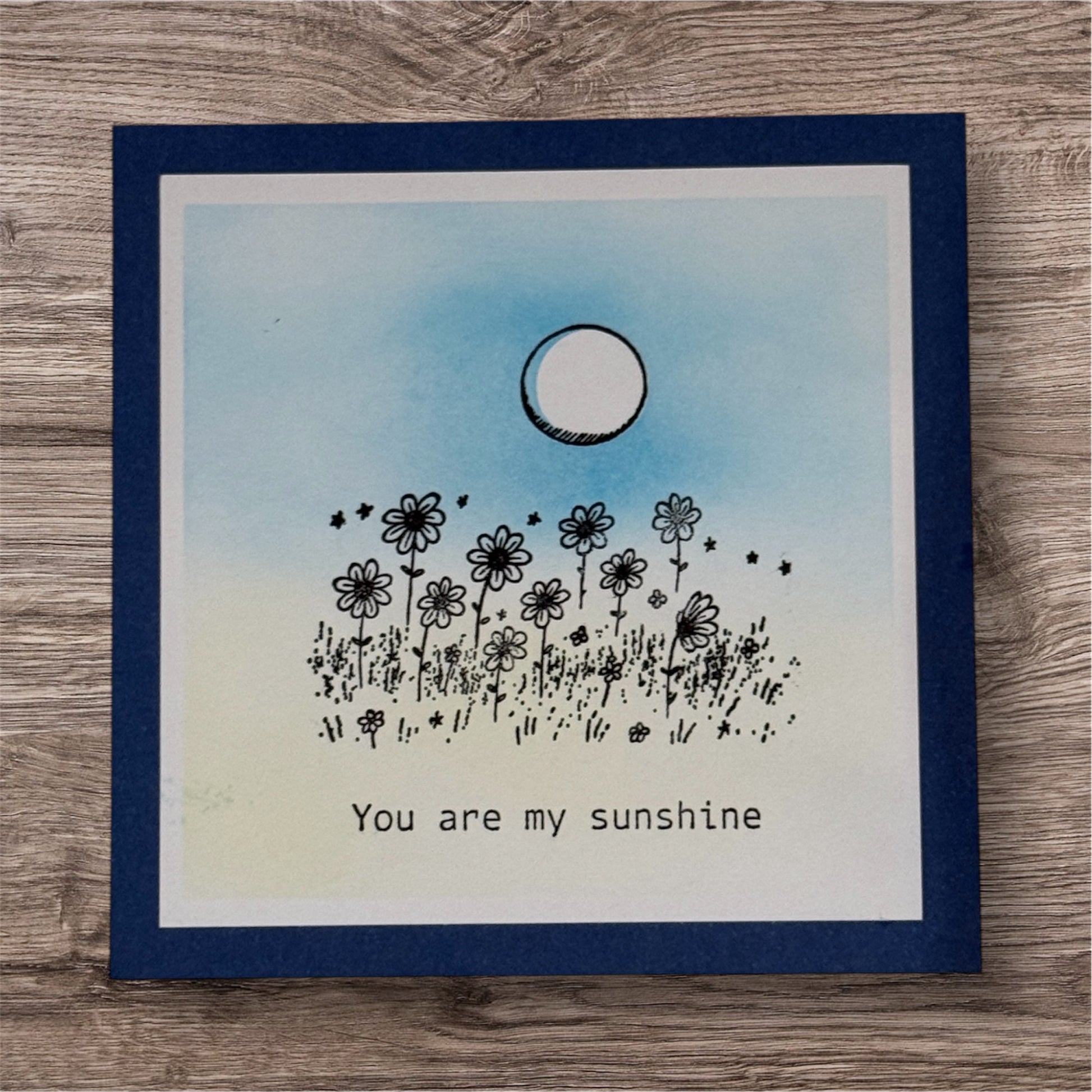 Card with floral design and 'You are my sunshine' text on a wooden surface