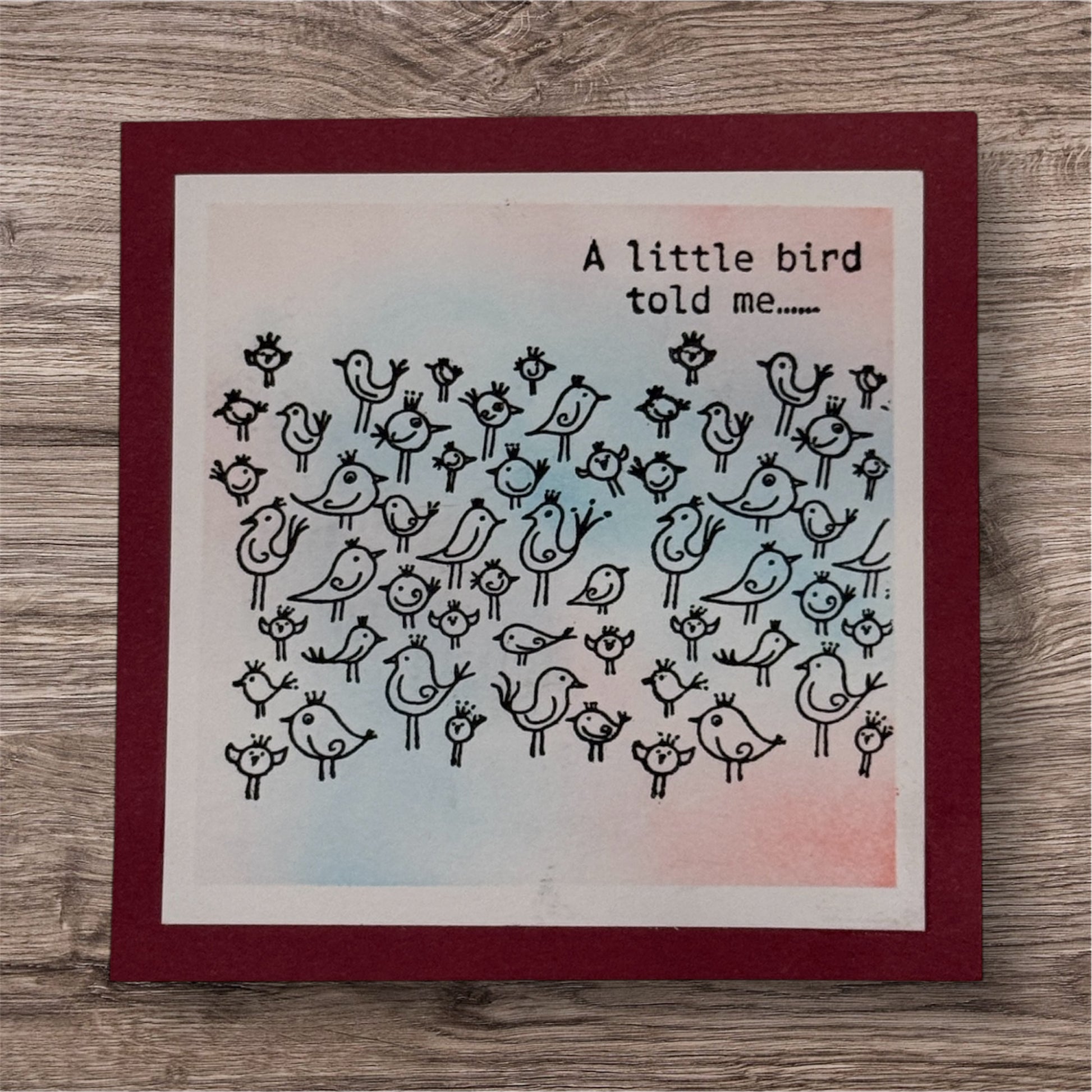Card with black bird illustrations and text on a wooden surface