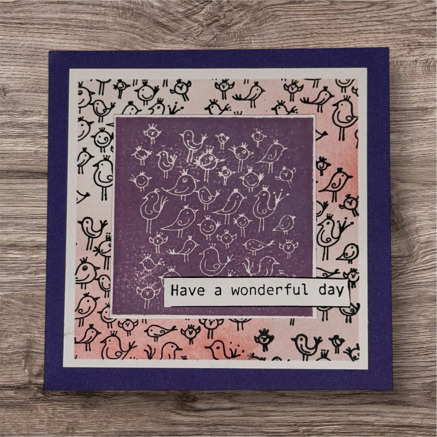 Greeting card with bird pattern and 'Have a wonderful day' text on a wooden surface