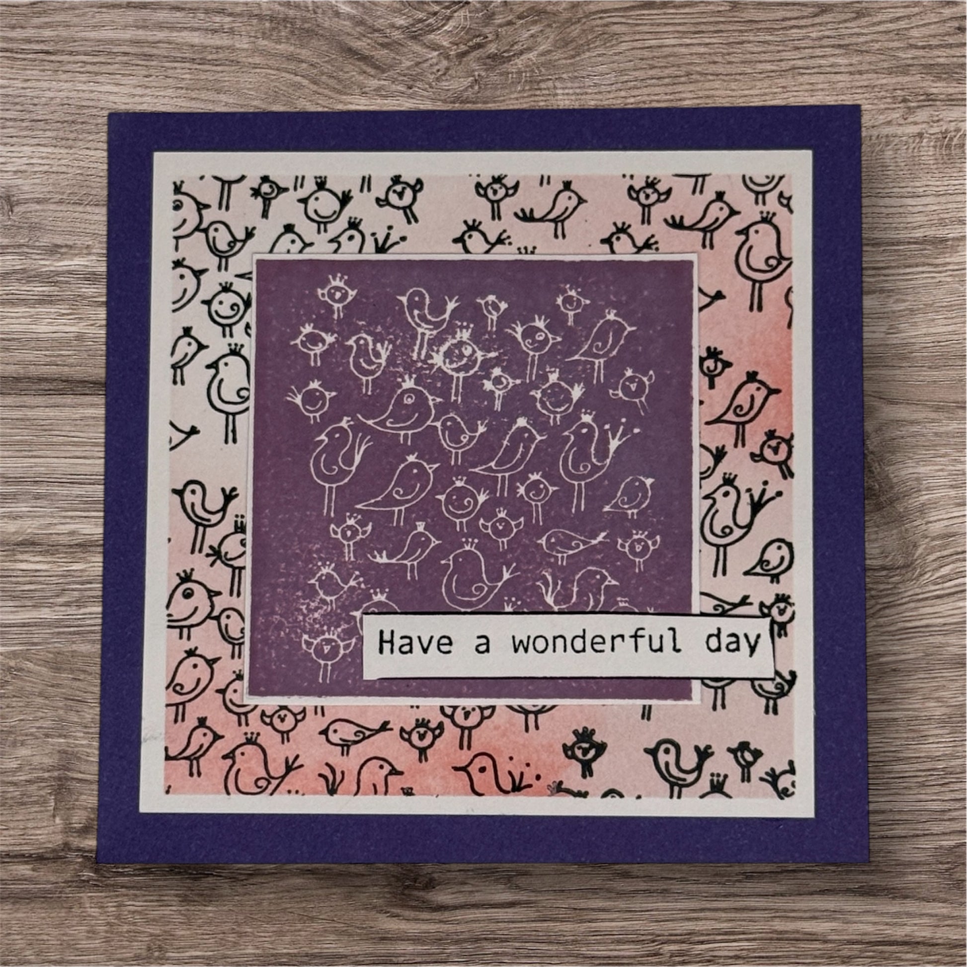 Greeting card with bird pattern and 'Have a wonderful day' text on a wooden surface