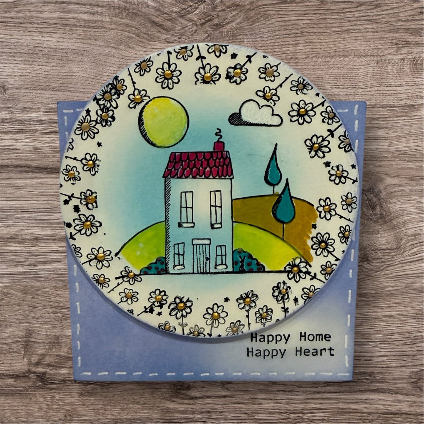 Decorative plate with a house illustration and floral patterns on a wooden surface
