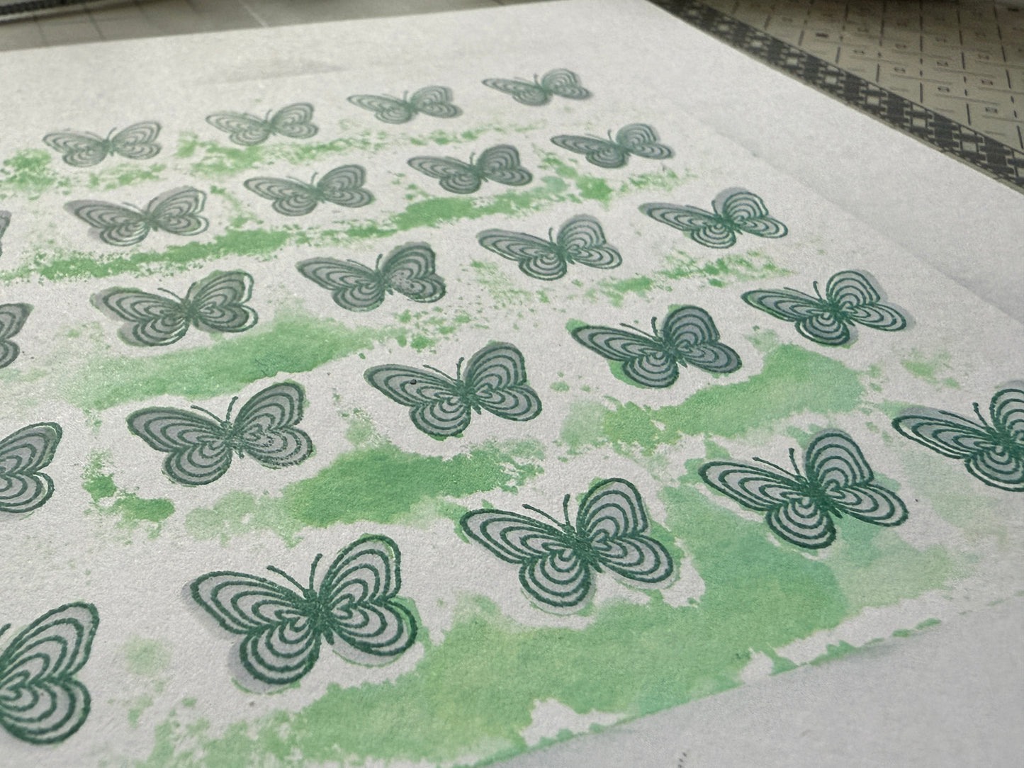 Sheet of paper with green butterfly patterns on a white background