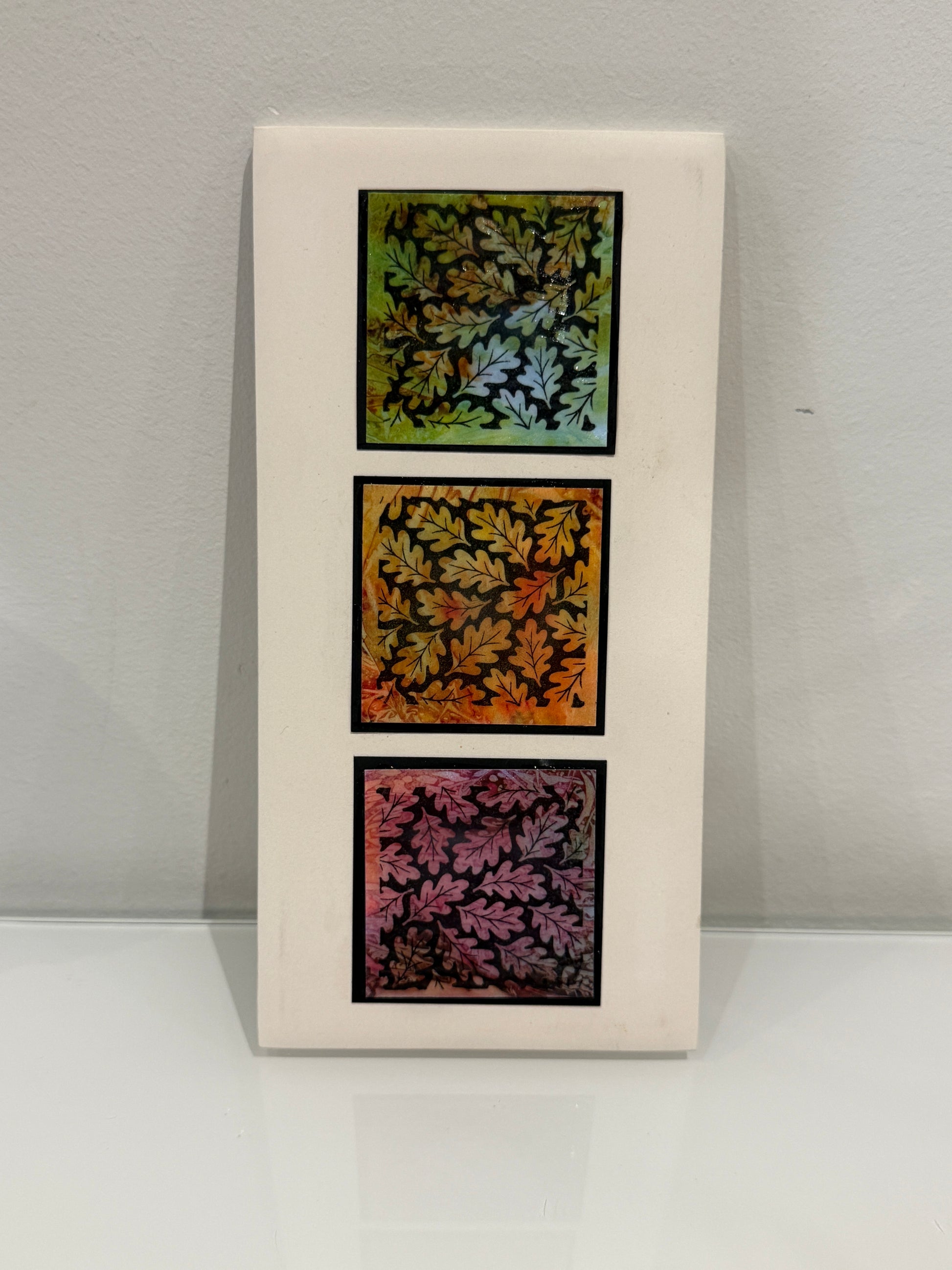 Three framed leaf-patterned artworks on a white wall
